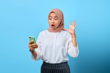 Cep telefonuna bakan ağzı açık Asyalı genç bir kadının portresi.