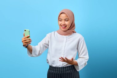 Başarımızı kutlamak için cep telefonuna bakan heyecanlı, genç Asyalı kadının portresi.