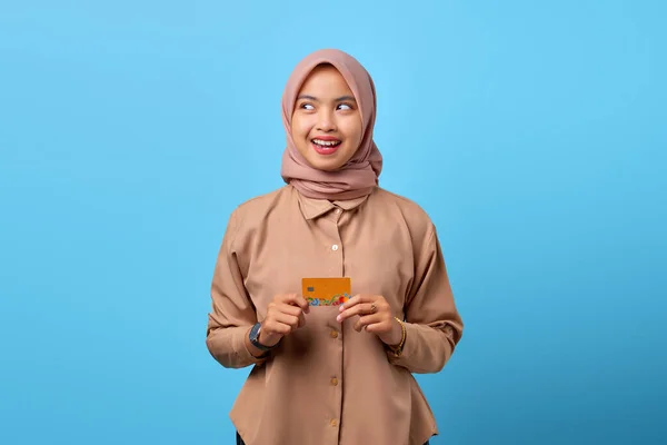 脇を見ながらクレジットカードを持っている若いアジアの女性の笑顔の肖像画 — ストック写真