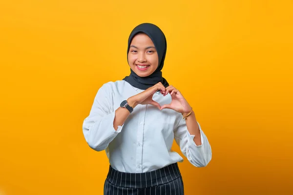 Gülümseyen Genç Asyalı Kadın Sarı Arka Planda Kalp Işaretleri Oluşturuyor — Stok fotoğraf