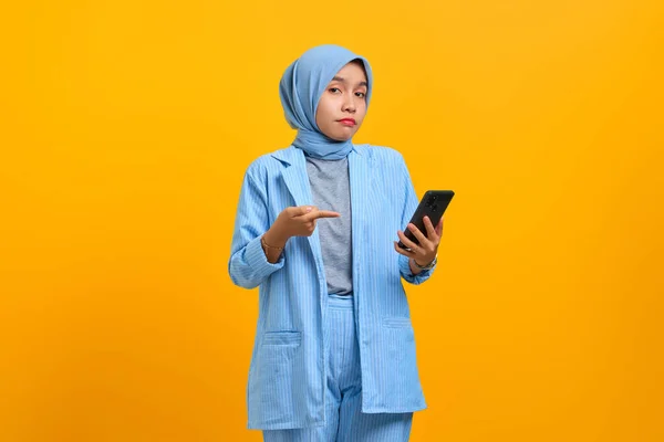 노란색 배경으로 고립된 손으로 스마트폰을 가리키는 아시아의 — 스톡 사진