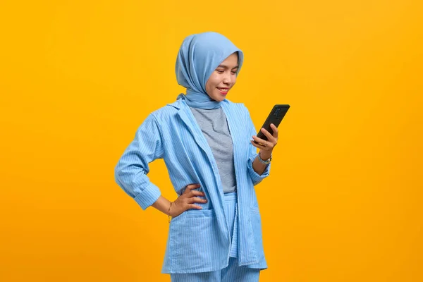 Vrolijke Jonge Aziatische Vrouw Zoek Naar Mobiele Telefoon Geïsoleerd Gele — Stockfoto