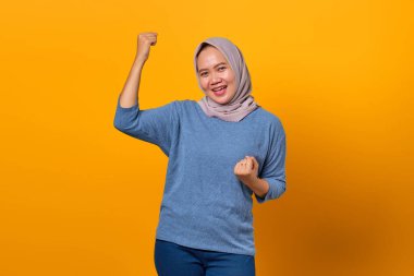 Sarı arka planda başarıyı kutlayan neşeli, çekici Asyalı kadın portresi