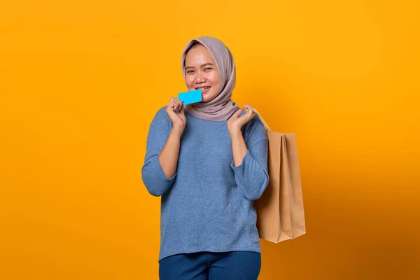 Retrato Mujer Asiática Excitada Sosteniendo Bolsa Compras Mordiendo Tarjeta Crédito — Foto de Stock