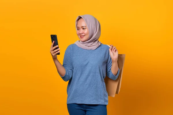 노란색 배경에 핸드폰 쇼핑백을 아시아 여성의 — 스톡 사진