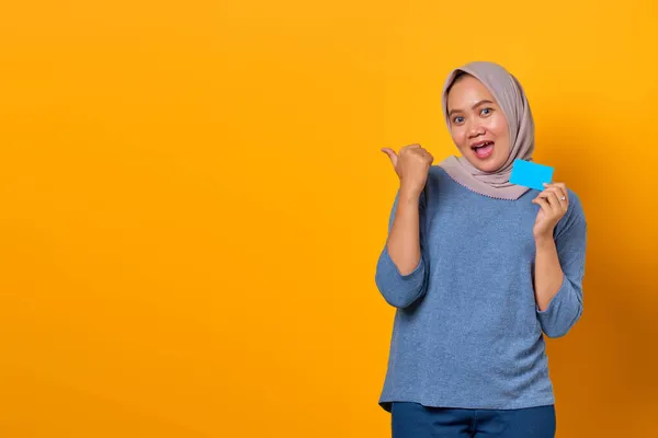 Retrato Mujer Asiática Excitada Sosteniendo Tarjeta Crédito Señalando Con Dedo —  Fotos de Stock