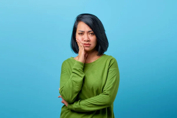 Portret Kobiety Azjatki Dotykającej Policzka Znudzonym Wyrazem Twarzy Niebieskim Tle — Zdjęcie stockowe