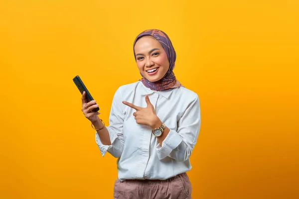 Portret Van Lachende Aziatische Vrouw Wijzen Smartphone Gele Achtergrond — Stockfoto