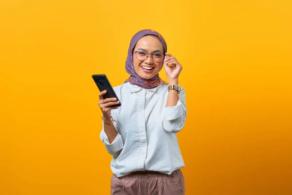 Sonriente Mujer Asiática Tocando Gafas Sosteniendo Teléfono Móvil Una Mano —  Fotos de Stock