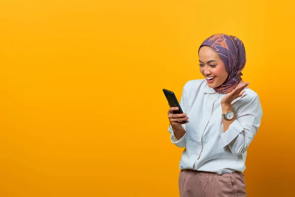 Fröhliche Asiatin Bekommt Unglaubliche Nachricht Auf Smartphone Vor Gelbem Hintergrund — Stockfoto