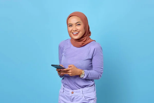 Mavi Arka Planda Cep Telefonu Kullanan Gülümseyen Asyalı Genç Kadının — Stok fotoğraf