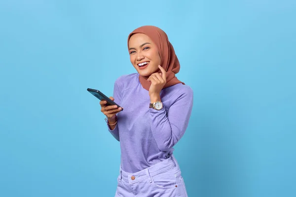 用蓝色背景的手机描绘笑容满面的年轻亚洲女人 — 图库照片