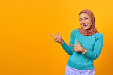 Gülümseyen Asyalı genç bir kadının portresi sarı arka plandaki fotokopi alanını gösteriyor.