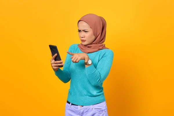 Geschokt Jonge Aziatische Vrouw Zoek Naar Smartphone Scherm Gele Achtergrond — Stockfoto