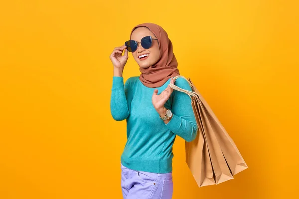 Fröhliche Junge Asiatin Mit Sonnenbrille Und Einkaufstaschen Auf Gelbem Hintergrund — Stockfoto