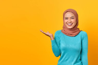 Gülümseyen Asyalı bir kadının portresi. Sarı arka planda, avuç içi izole edilmiş fotokopi alanı gösteriyor.