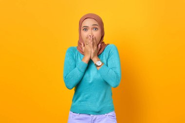 Sarı arka planda ağzı olan genç Asyalı kadın şok oldu.