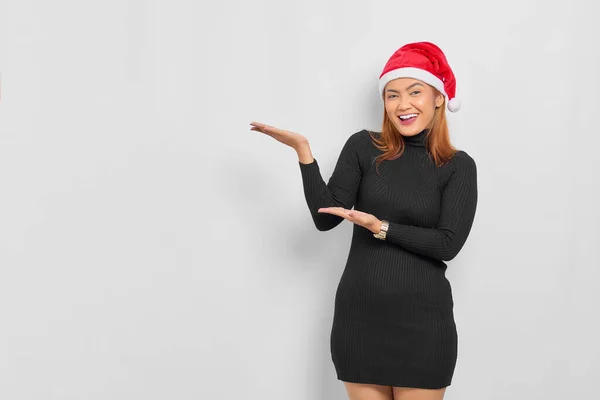 身穿圣诞帽 面带微笑的年轻亚洲女子的画像 在白色背景的手掌上展示复制空间 — 图库照片