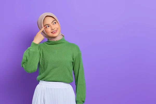 紫色の背景に隔離された素晴らしいアイデアを持って 頭の上に指で離れて見て笑って緑のセーターの美しい若いアジアの女性 — ストック写真
