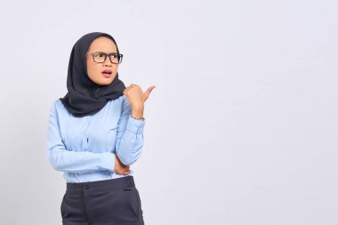 Beyaz arka planda izole edilmiş fotokopi alanını işaret eden şok olmuş genç Asyalı kadın portresi