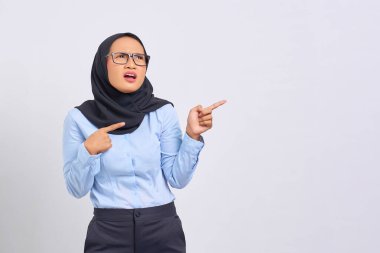 Beyaz arka planda izole edilmiş fotokopi alanını işaret eden şok olmuş genç Asyalı kadın portresi