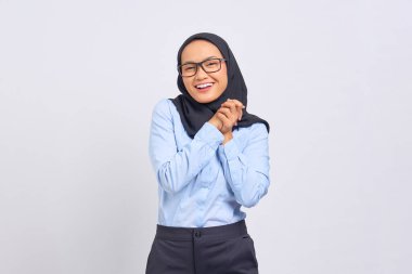 Neşeli, genç Asyalı bir kadının portresi, ellerini ovuşturuyor ve beyaz arka planda izole edilmiş kameraya bakıyor.