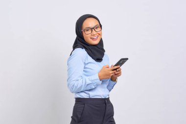 Beyaz arka planda izole edilmiş cep telefonu kullanan gülümseyen Asyalı genç kadının portresi