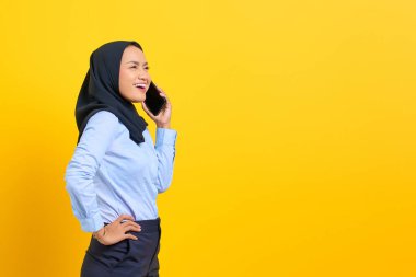 Cep telefonuyla konuşan ve sarı arka planda izole edilmiş mutlu Asyalı bir kadının portresi.