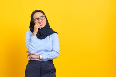 Düşünceli, genç Asyalı bir kadının portresi sarı arka planda izole edilmiş bir soruyu ciddi ciddi düşünüyor.