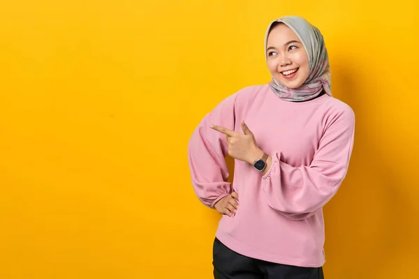 陽気若いですアジアの女性でピンクシャツPointing指でコピースペース上の黄色の背景 — ストック写真