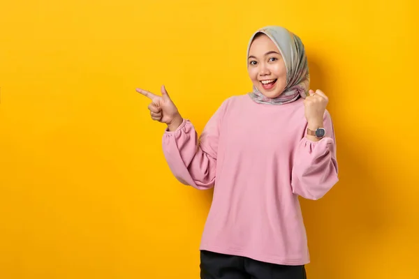 興奮若いですアジアの女性でピンクシャツPointing指でコピースペース上の黄色の背景 — ストック写真