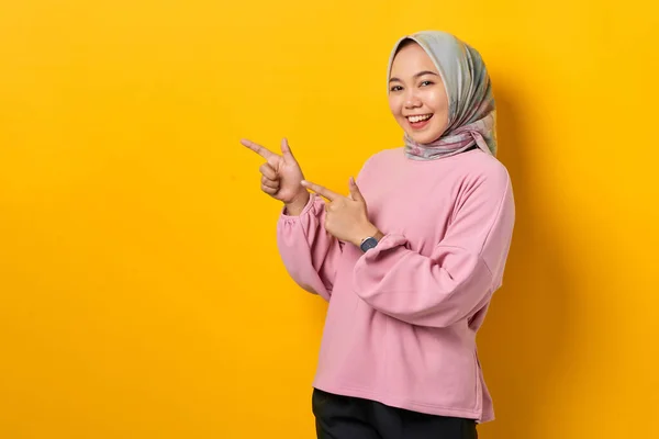Wesoła Młoda Azjatka Różowej Koszuli Wskazująca Palcem Przestrzeń Żółtym Tle — Zdjęcie stockowe