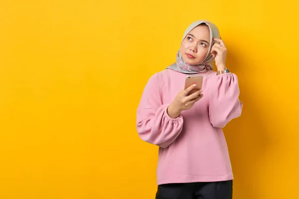 Pensive Mladá Asijská Žena Růžové Košili Pomocí Smartphone Myšlení Otázku — Stock fotografie