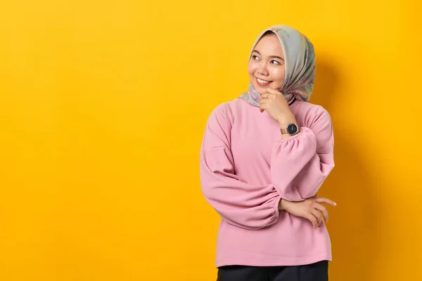 笑顔若いですアジアの女性でピンクシャツで離れて見ますコピースペース上の黄色の背景 — ストック写真