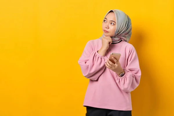 Pensive Mladá Asijská Žena Růžové Košili Pomocí Smartphone Myšlení Otázku — Stock fotografie