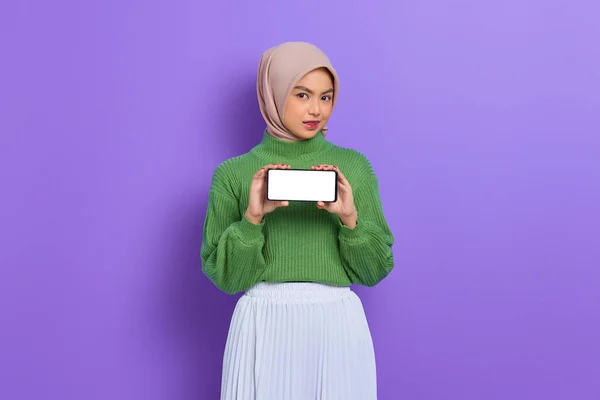 美しいですアジアの女性で緑のセーターとHijabショーブランクスクリーン携帯電話絶縁以上紫の背景 — ストック写真