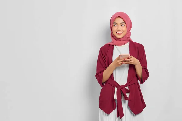 穿着休闲装 头戴头巾 用手机微笑着美丽的亚洲女人 望着被白色背景隔开的空白空间 人们的宗教生活方式概念 — 图库照片