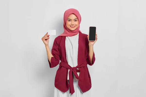 身穿休闲装 头戴头巾 手持带有空白屏幕的手机 手里拿着白色背景的信用卡 是一位快乐而美丽的亚洲女人 人们的宗教生活方式概念 — 图库照片