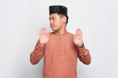 Ciddi Asyalı genç Müslüman adam dur hareketi yapıyor ve beyaz arka planda izole edilmiş reddedildiğini gösteriyor.