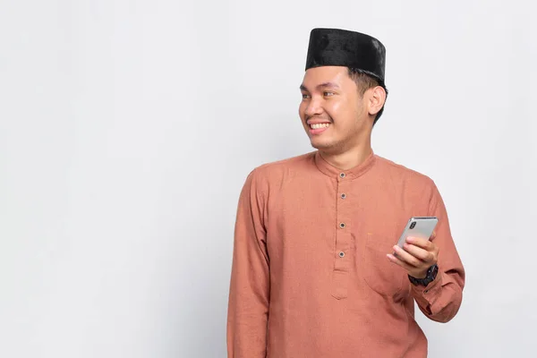 Pemuda Muslim Asia Yang Ceria Menggunakan Ponsel Dan Memandang Jauh — Stok Foto
