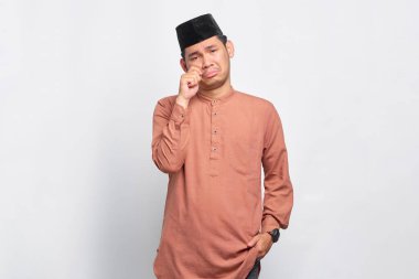 Genç Asyalı Müslüman adam ağlamak istiyor. Depresyonda. Beyaz arka planda izole edilmiş bir sorun var.