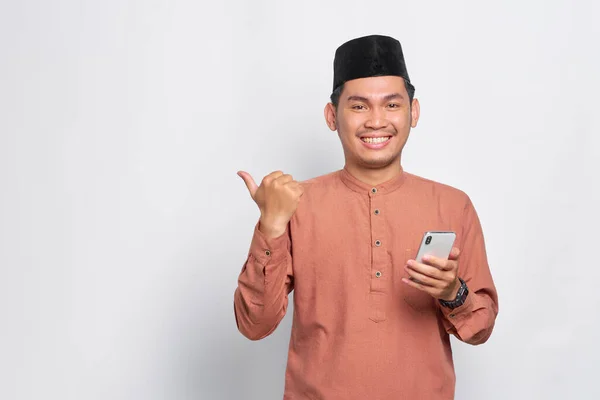 Glada Unga Asiatiska Muslimska Man Som Håller Mobiltelefon Och Pekar — Stockfoto