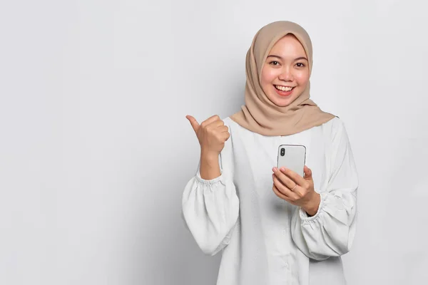 Cheerful Young Asian Muslim Woman Holding Mobile Phone Pointing Away — Stock Photo, Image