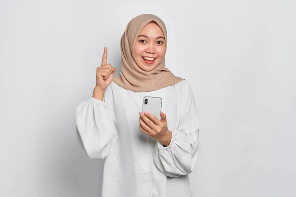 Sorrindo Jovem Mulher Muçulmana Asiática Segurando Telefone Celular Apontando Dedo — Fotografia de Stock