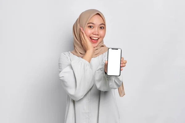 携帯電話の空白の画面を示す素晴らしい若いアジアのイスラム教徒の女性は白い背景に隔離されたアプリをお勧めします — ストック写真