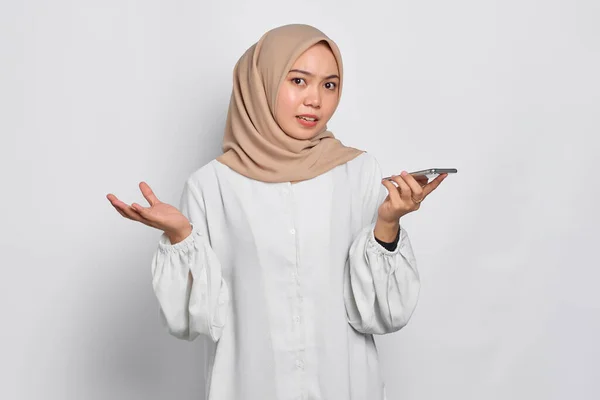 Запутавшаяся Молодая Азиатка Мусульманка Помощью Голосового Помощника Смартфоне Изолирована Белом — стоковое фото