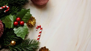 Yeşil çam ağacı yaprakları, pembe noel süslemeleri yumuşak mermer arka planda şeker kamışları, parlak ve süslü pembe noel süslemeleri. Basit ve yaratıcı Noel konsepti.