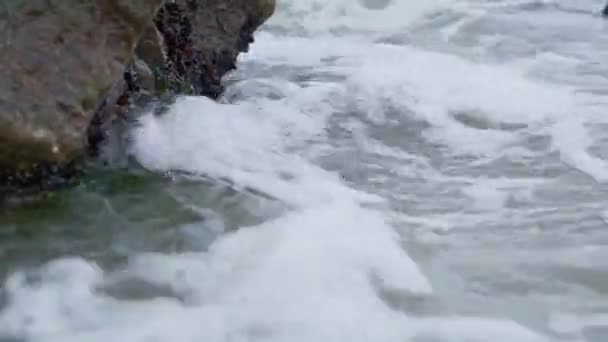 Primer plano de las olas marinas con espuma corriendo a tierra y golpeando rocas rocosas — Vídeos de Stock