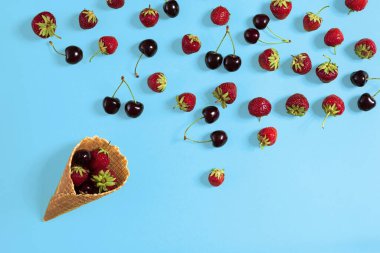 Taze sulu çilek ve tatlı waffle koni üzerinde mavi arka plan, üstten görünüm.