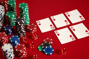 Kumarhane kumarhanesi poker ekipmanları ve eğlence konsepti. Kırmızı arka planda kart ve fiş oyunlarının kapanışı. Kraliyet floş kalbi..